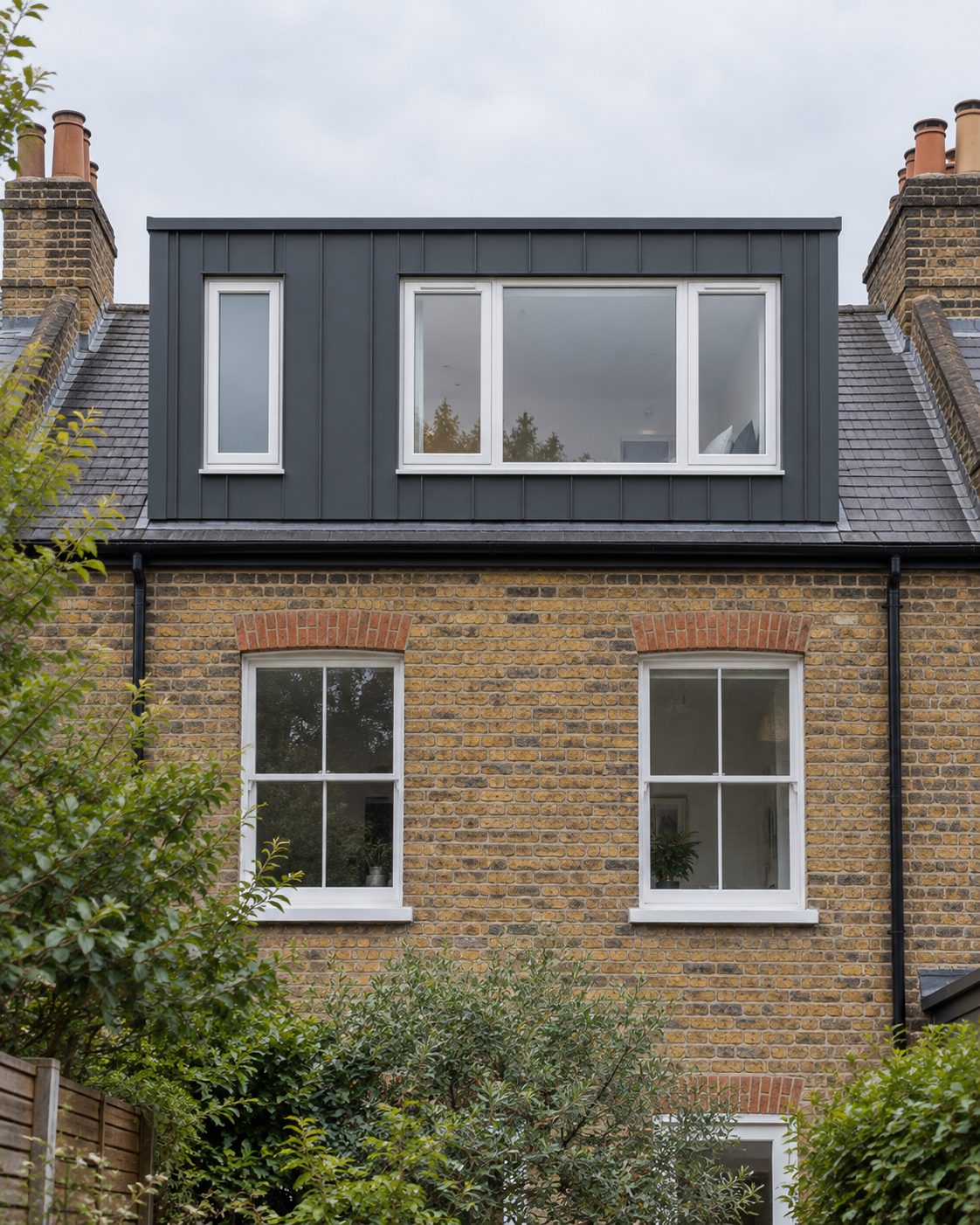 Rear dormer loft conversion clad in dark standing-seam metal on a London stock-brick terrace